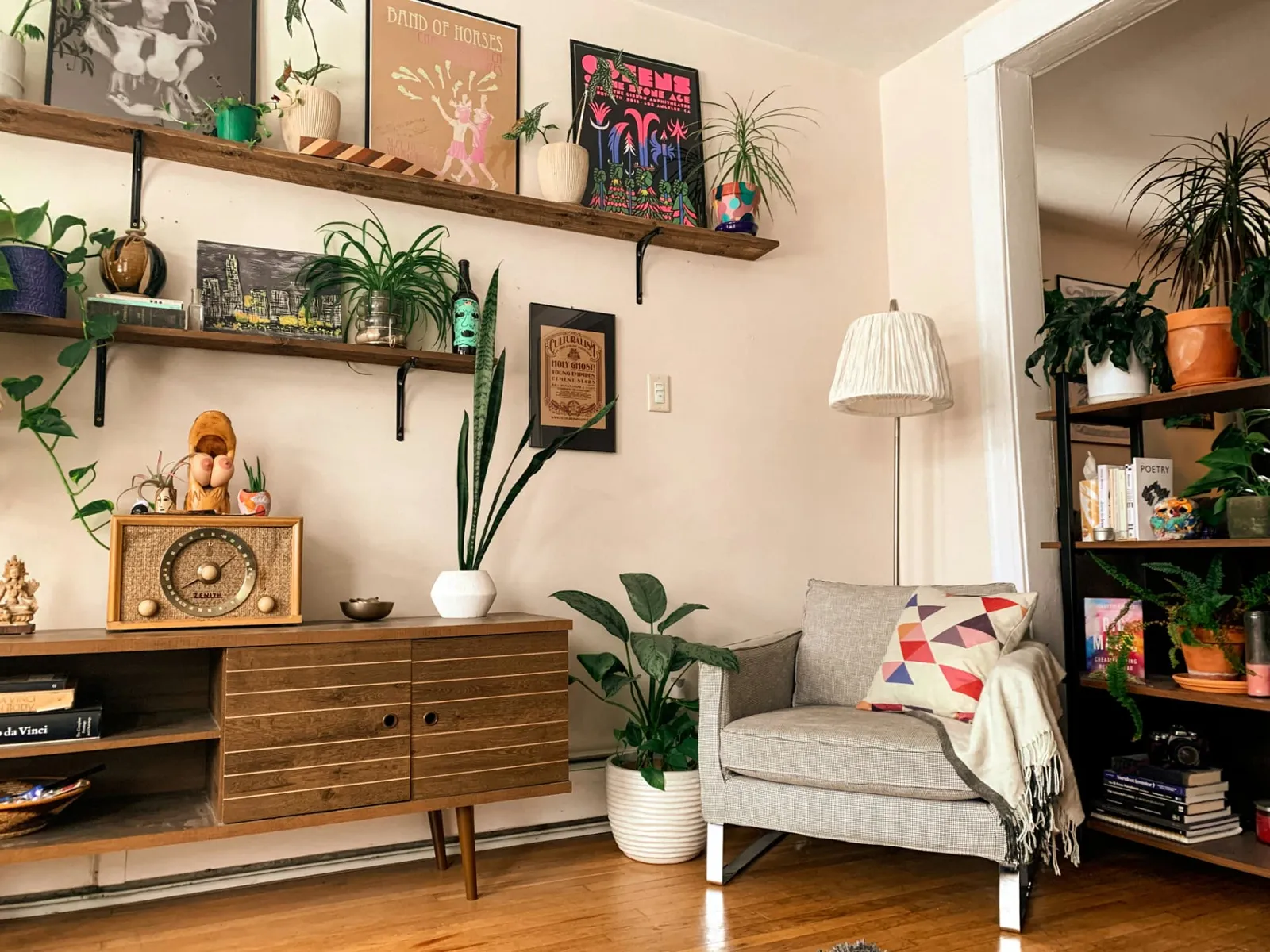 Warm apartment interior with plants, shelving and a comfortable chair.